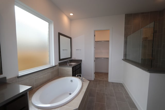 bathroom with tiled bath, tile patterned flooring, and vanity