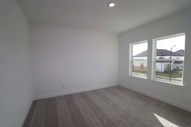 unfurnished room featuring dark colored carpet