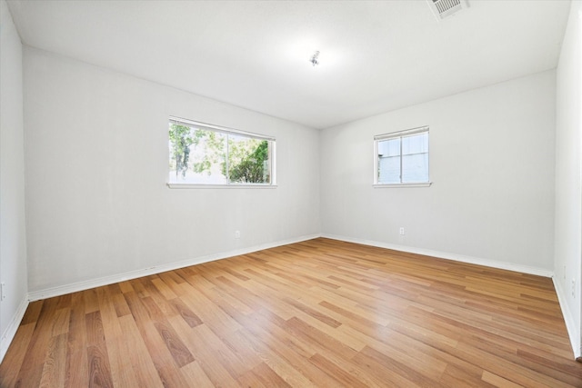 unfurnished room with a healthy amount of sunlight and light hardwood / wood-style floors