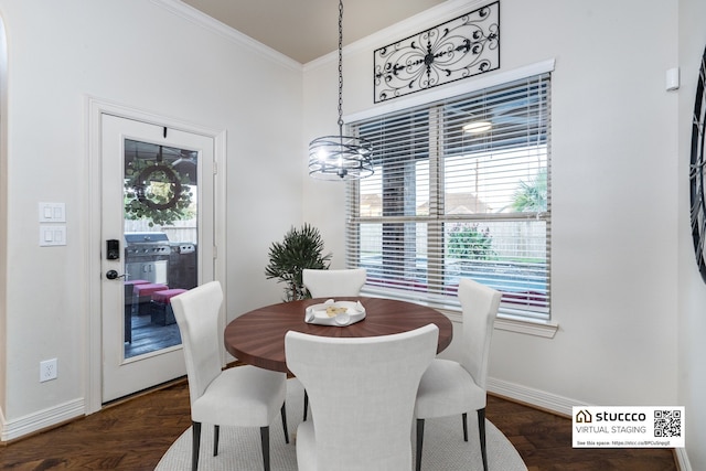 dining area with dark hardwood / wood-style floors, ornamental molding, and a notable chandelier