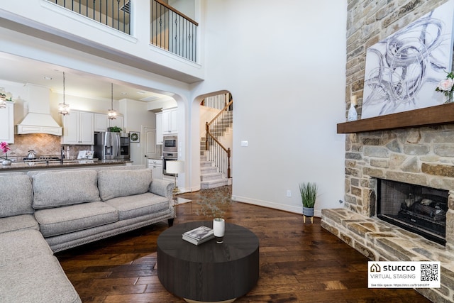 living room featuring a fireplace, dark wood-type flooring, and a high ceiling