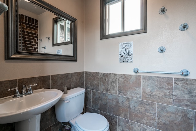 bathroom with toilet, tile walls, and sink