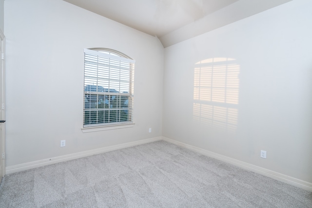 carpeted empty room with lofted ceiling