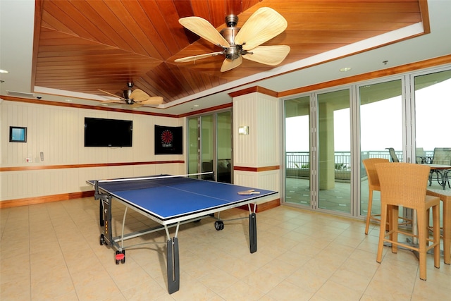 recreation room with ceiling fan, a raised ceiling, wood ceiling, and crown molding