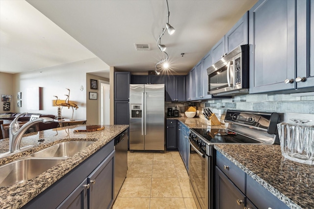 kitchen featuring decorative backsplash, rail lighting, stainless steel appliances, sink, and light tile patterned floors