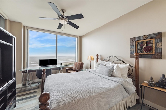 bedroom with ceiling fan, expansive windows, and hardwood / wood-style flooring