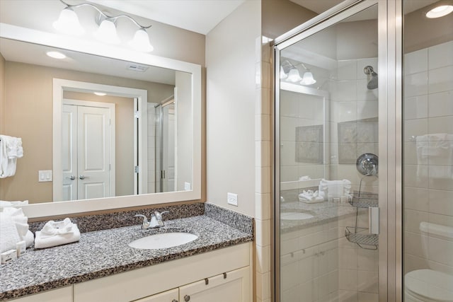 bathroom with visible vents, vanity, a stall shower, and toilet