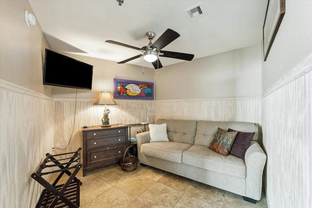 living room featuring ceiling fan and wood walls