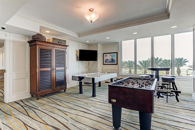 rec room with a tray ceiling, ornamental molding, and light colored carpet