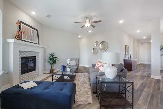 living room featuring a tiled fireplace, hardwood / wood-style floors, and ceiling fan