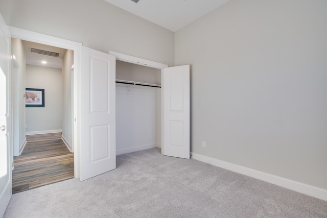 unfurnished bedroom with light colored carpet and a closet