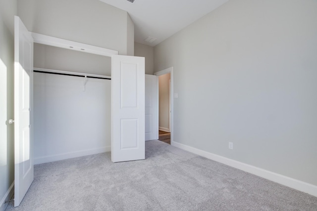 unfurnished bedroom featuring a towering ceiling, light colored carpet, and a closet