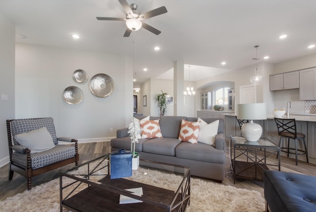 living room featuring sink, ceiling fan with notable chandelier, and light hardwood / wood-style flooring