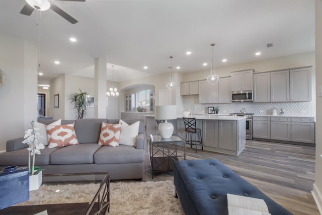 living room featuring sink, light hardwood / wood-style floors, and ceiling fan with notable chandelier