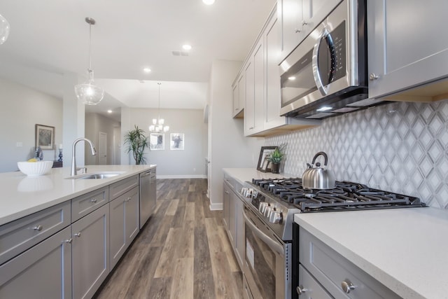 kitchen featuring stainless steel appliances, gray cabinets, and decorative light fixtures