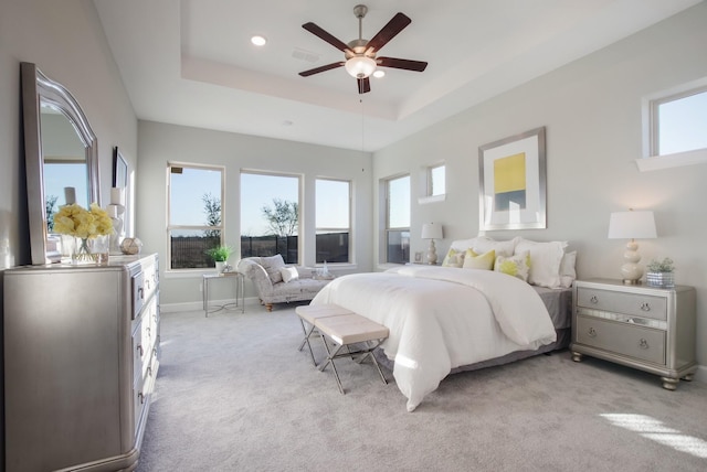 bedroom featuring ceiling fan, a tray ceiling, and light colored carpet