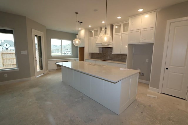 kitchen featuring a kitchen island, tasteful backsplash, white cabinetry, custom exhaust hood, and hanging light fixtures