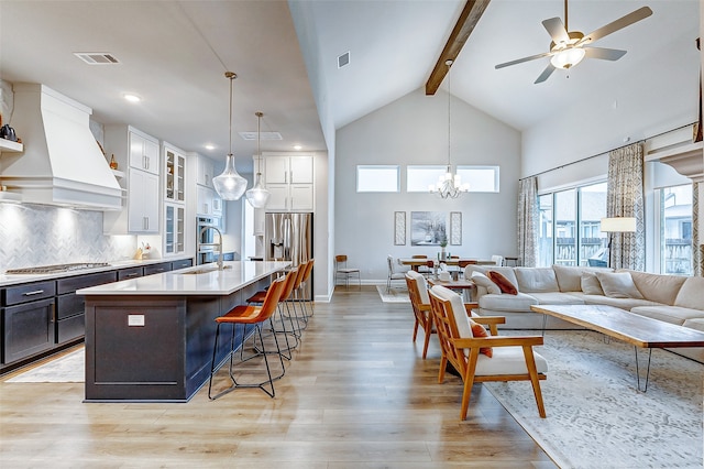 kitchen with white cabinets, light hardwood / wood-style floors, hanging light fixtures, and custom exhaust hood