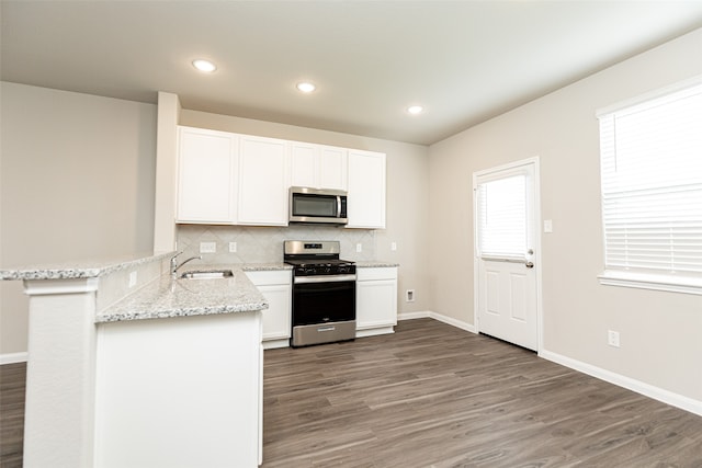 kitchen with stainless steel appliances, white cabinetry, sink, kitchen peninsula, and dark hardwood / wood-style flooring