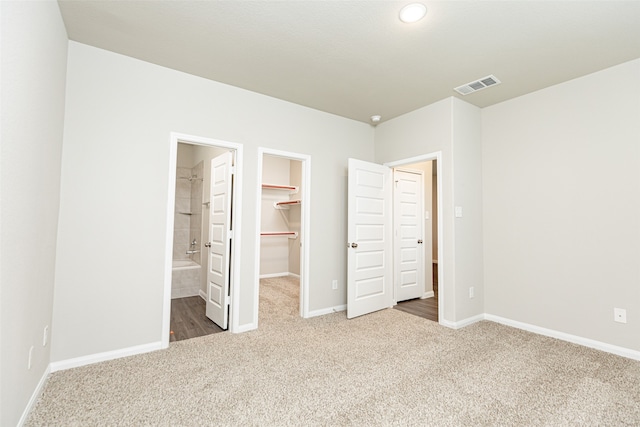 unfurnished bedroom with connected bathroom, a closet, a spacious closet, and carpet floors