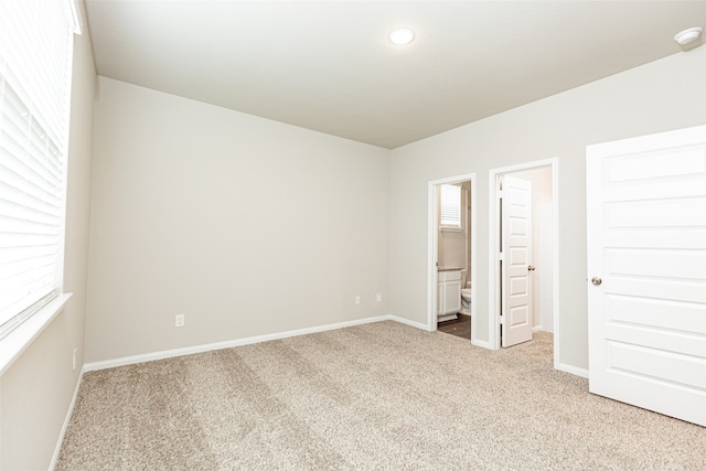 unfurnished bedroom featuring connected bathroom and carpet flooring