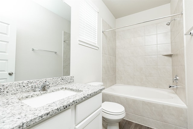 full bathroom with hardwood / wood-style floors, vanity, tiled shower / bath combo, and toilet