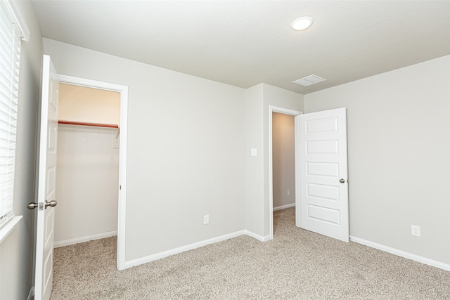 unfurnished bedroom featuring a closet, a spacious closet, and carpet flooring