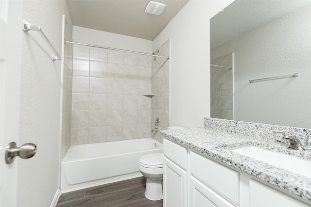 full bathroom featuring a textured ceiling, wood-type flooring, vanity, toilet, and tiled shower / bath combo