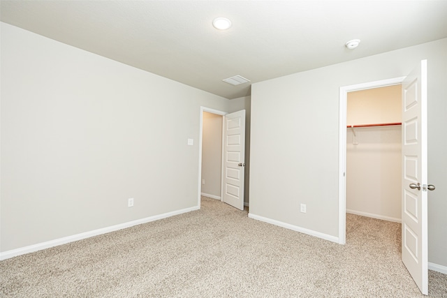 unfurnished bedroom featuring light colored carpet, a closet, and a spacious closet