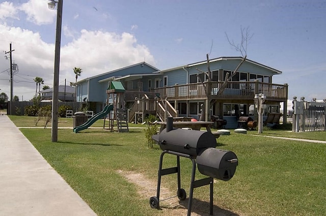 view of play area with a wooden deck and a lawn