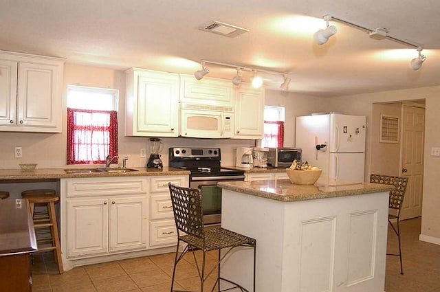 kitchen with white cabinetry, sink, light stone countertops, and white appliances