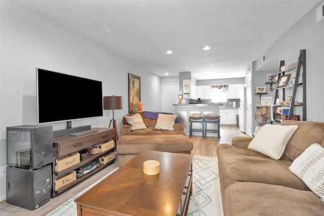 living room with light wood-type flooring and a textured ceiling