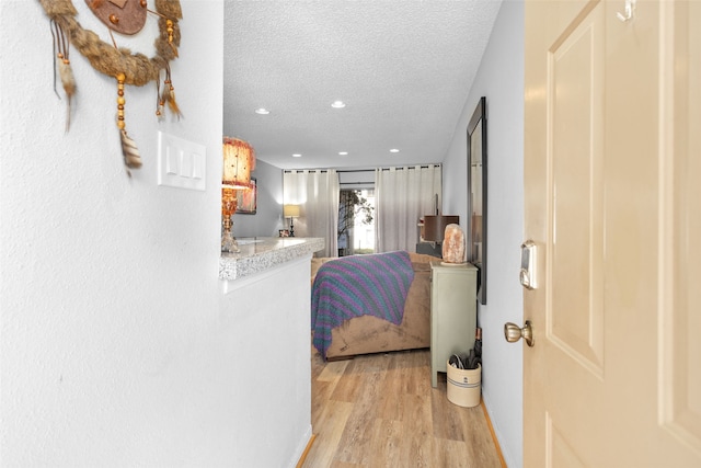 corridor featuring light hardwood / wood-style flooring and a textured ceiling