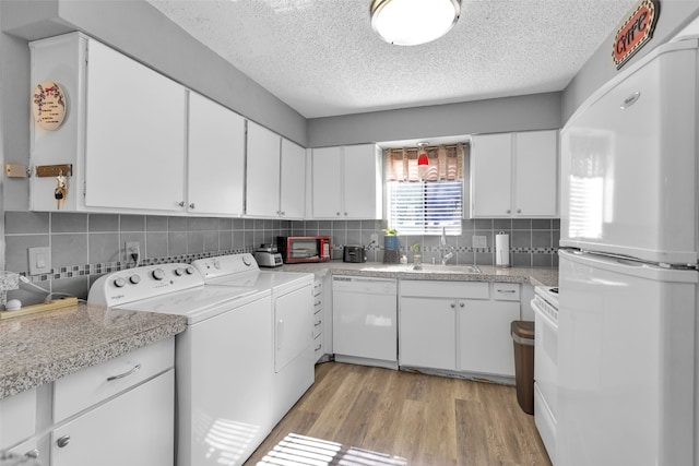 clothes washing area featuring light wood-type flooring, a textured ceiling, sink, and washing machine and clothes dryer