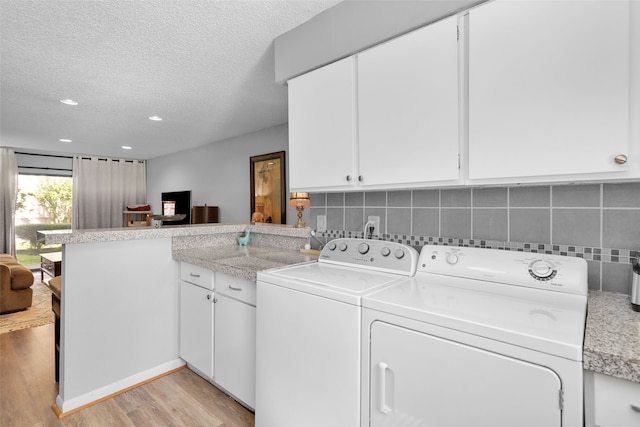 laundry room featuring cabinets, light hardwood / wood-style floors, a textured ceiling, and washer and dryer