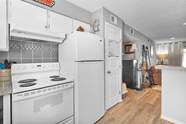 kitchen featuring white cabinets, decorative backsplash, a textured ceiling, light wood-type flooring, and white appliances