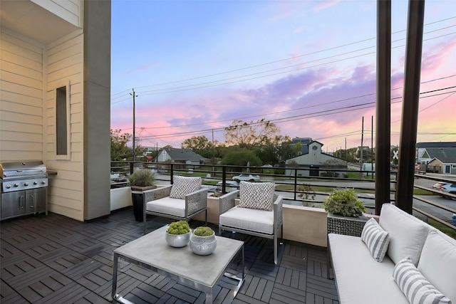 patio terrace at dusk with area for grilling, an outdoor living space, and a balcony