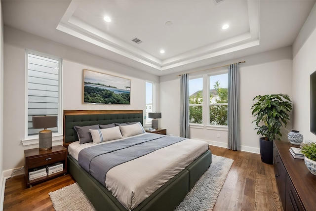 bedroom with dark hardwood / wood-style flooring and a tray ceiling