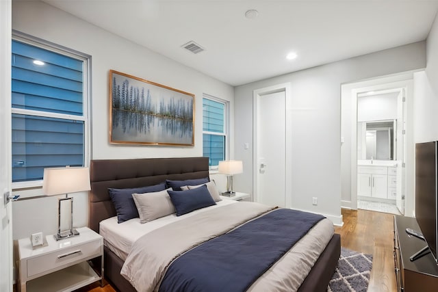 bedroom with connected bathroom and wood-type flooring