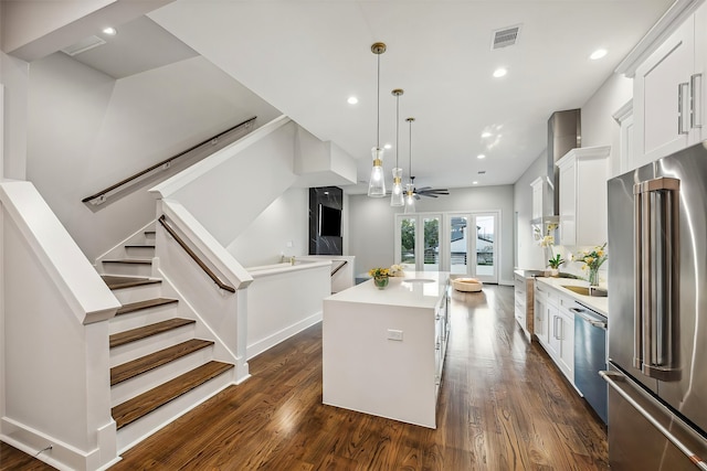 kitchen featuring dark wood-type flooring, a center island, white cabinets, pendant lighting, and appliances with stainless steel finishes