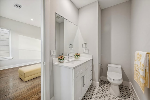 bathroom featuring toilet, vanity, and hardwood / wood-style floors