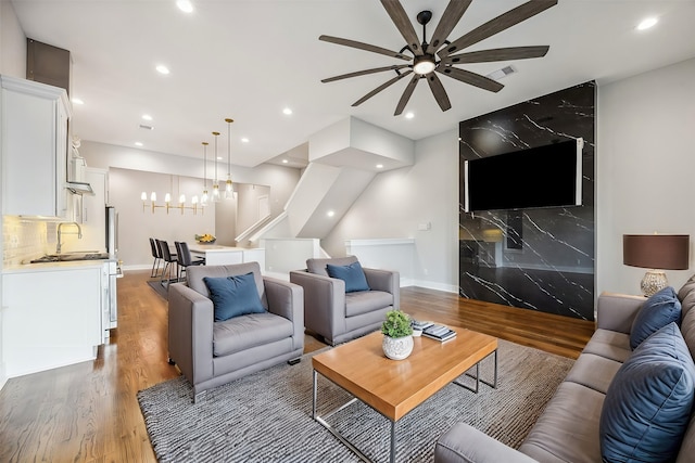 living room featuring ceiling fan with notable chandelier and wood-type flooring