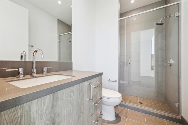 bathroom with tile patterned flooring, vanity, a shower with door, and toilet