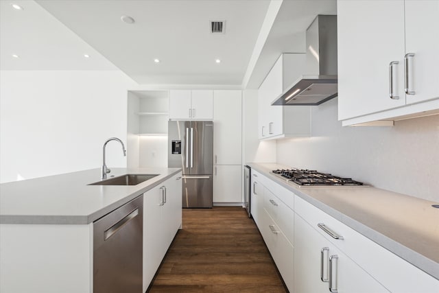 kitchen featuring sink, dark wood-type flooring, stainless steel appliances, wall chimney range hood, and white cabinets