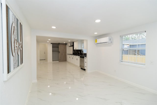 interior space with white cabinetry, dishwasher, a barn door, a wall unit AC, and decorative backsplash