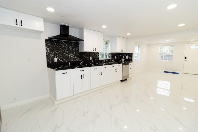 kitchen featuring backsplash, sink, stainless steel dishwasher, wall chimney exhaust hood, and white cabinetry