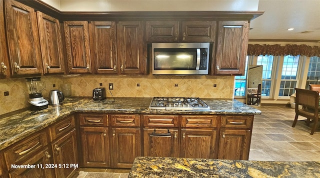 kitchen featuring stainless steel appliances, backsplash, and dark stone counters