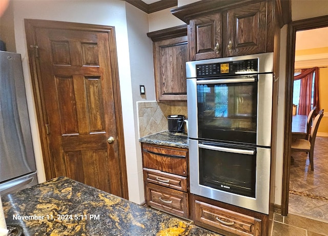 kitchen with backsplash, dark stone counters, stainless steel appliances, and dark brown cabinetry