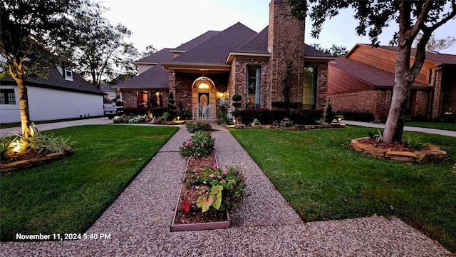 view of front of home with a front yard, a chimney, a shingled roof, and brick siding