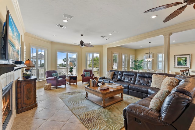 tiled living room with a fireplace, ceiling fan, ornate columns, and crown molding